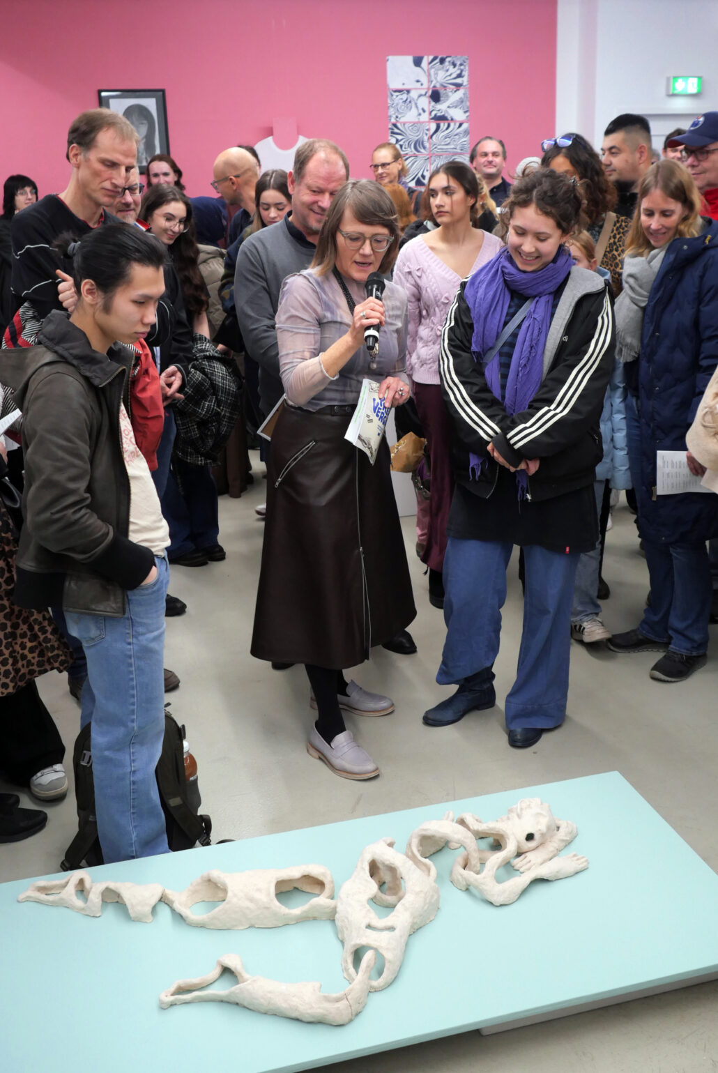 Viele Menschen stehen in einer Galerie vor einem Kunstwerk.